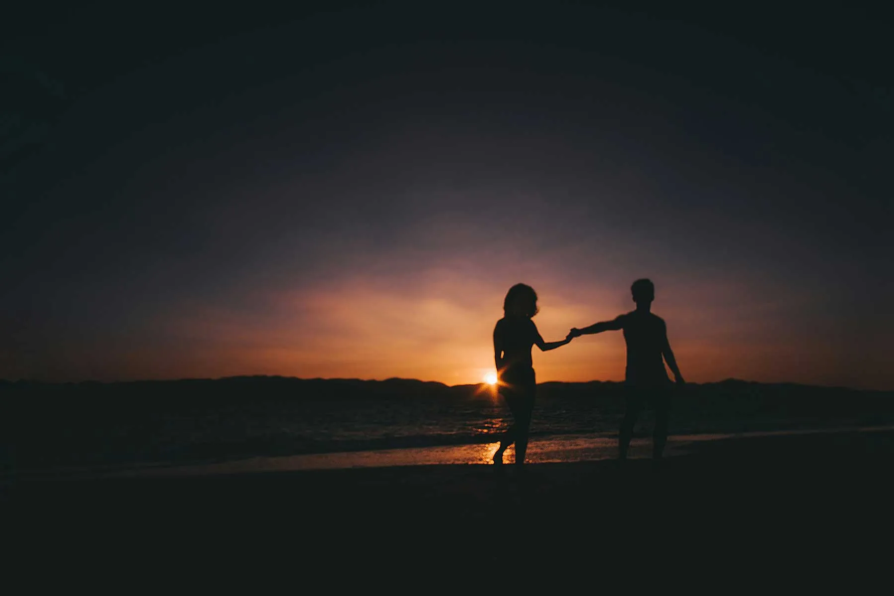 A couple walking on the beach at sunset