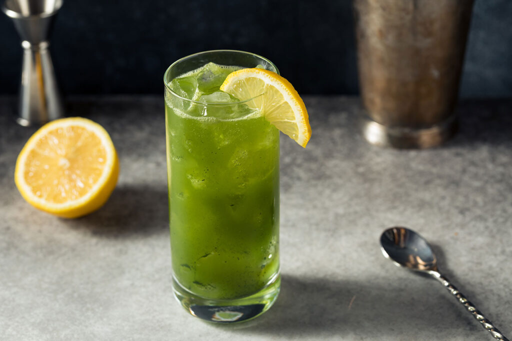 Refreshing green tropical drink with ice and lemon garnish served at Drake Bay Greenleaf